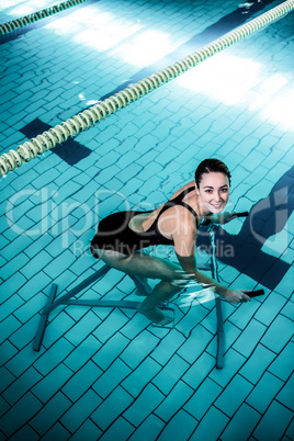 Fit smiling woman cycling on a swimming bike