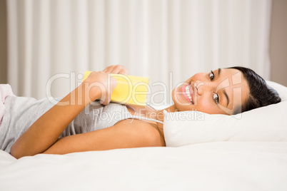 Smiling brunette on bed with book