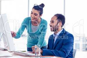 Happy businesswoman explaining to coworker over PC