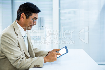 Smiling asian businessman using tablet