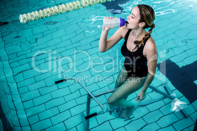 Fit woman cycling while drinking water