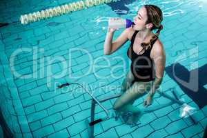 Fit woman cycling while drinking water
