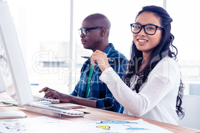 Portrait of businesswoman with colleague at desk