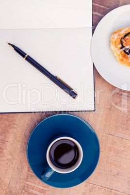 High angle view of pen on notepad by food and coffee at table