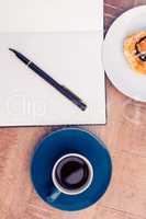 High angle view of pen on notepad by food and coffee at table