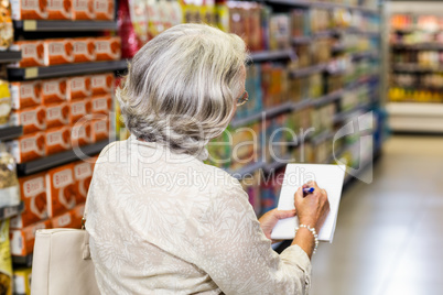 Senior woman checking list at the supermarket