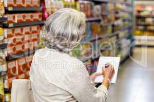 Senior woman checking list at the supermarket