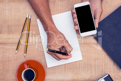 Overhead view of businessman hand holding smart phone while writ