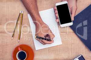 Overhead view of businessman hand holding smart phone while writ