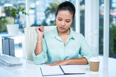 Thoughtful young businesswoman looking notes