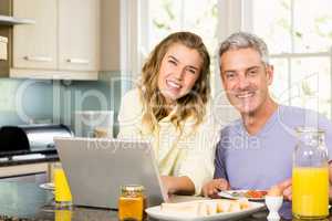 Happy couple using laptop and having breakfast