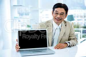 Smiling asian businessman showing his laptop