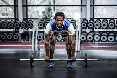 Concentrated muscular man lifting barebell