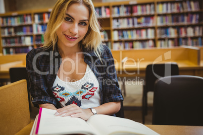 Smiling student reading a book at table