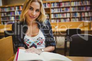 Smiling student reading a book at table