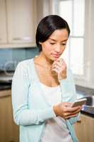 Thoughtful brunette using smartphone