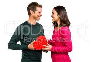 Happy young couple holding heart shaped gift