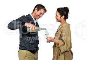 Smiling man pouring wine in glass with woman