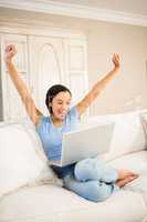 Happy woman using laptop and raising arms