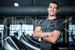Muscular man on treadmill with crossed arms