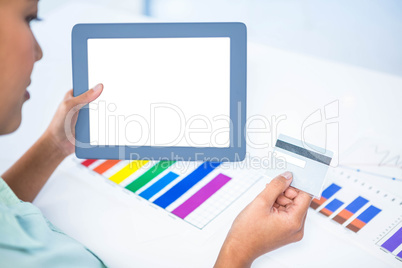 Businesswoman using her digital tablet while holding a credit ca