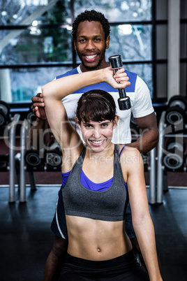 Fit woman doing dumbbells exercise with trainer