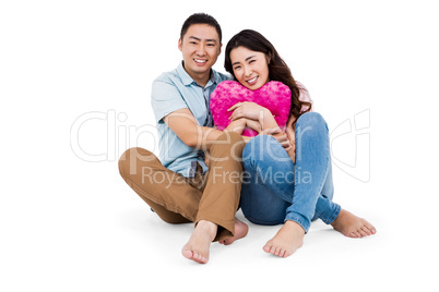 Happy young couple with heart shape pillow