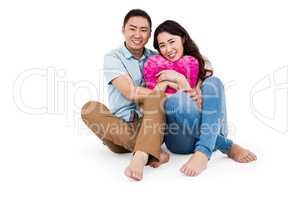 Happy young couple with heart shape pillow
