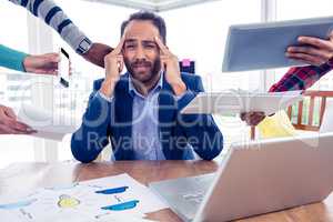 Stressful businessman by colleagues in creative office