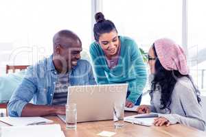 Young business people discussing over laptop in office