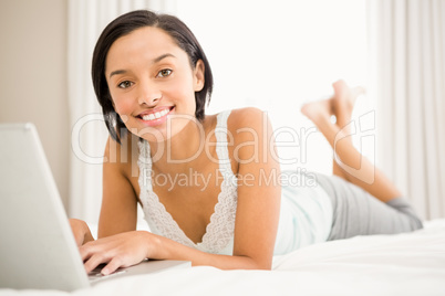 Smiling brunette using laptop