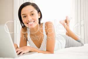 Smiling brunette using laptop