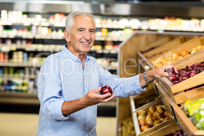 Smiling senior man holding red onion