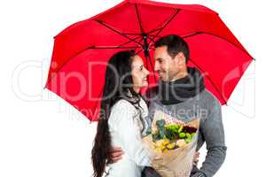 Smiling couple holding umbrella and bouquet