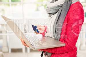 Woman using laptop and holding credit card