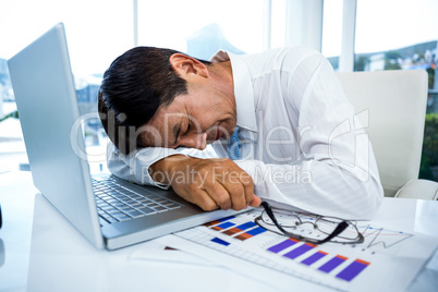 Exhausted businessman sleeping on his laptop