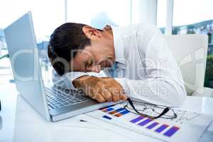 Exhausted businessman sleeping on his laptop