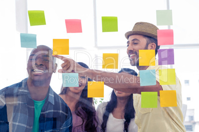 Businessman pointing while colleagues standing against adhesive