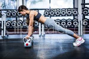 Fit woman doing push ups with kettlebells