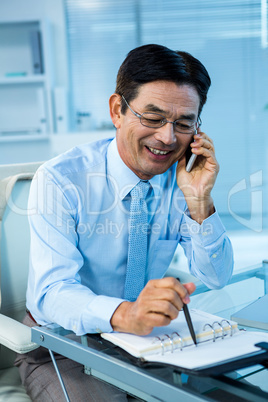 Smiling asian businessman calling someone