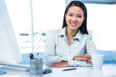 Confident businesswoman sitting on desk posing for camera