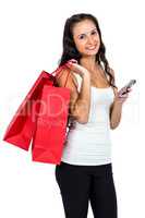 Smiling woman holding shopping bags and using smartphone