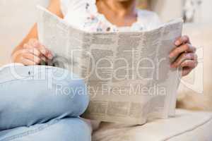 Mid section of woman reading newspaper