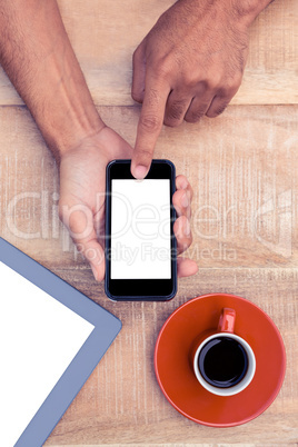 Person using smart phone by coffee and tablet on table