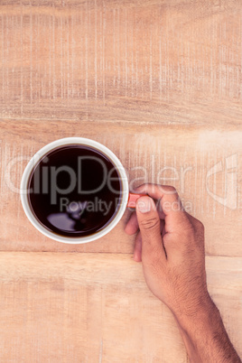 Businessman holding black coffee on desk