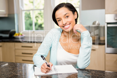 Smiling brunette writing on note pad