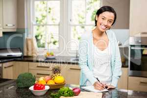 Smiling brunette writing on note pad