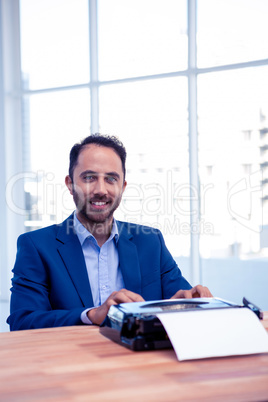 Portrait of smiling businessman working on typewriter  at office