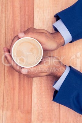 Businessman holding disposable coffee cup at desk