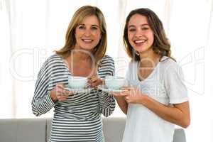 Mother and daughter holding cups